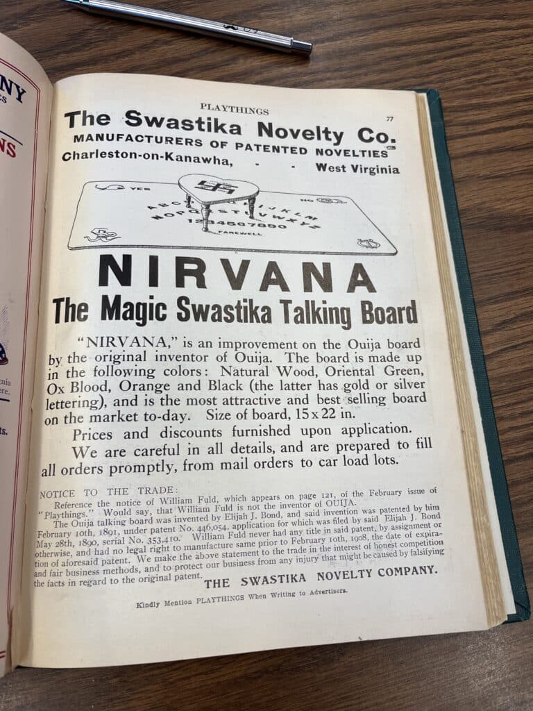 Illustration of An ad for the Swastika talking board created by Elijah J. Bond with a notice concerning William Fuld’s claim to the Ouija patent. Playthings, June 1908.